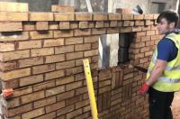 person apply mortar to brick wall