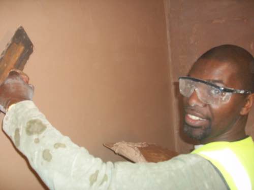 person applying plaster to a wall area