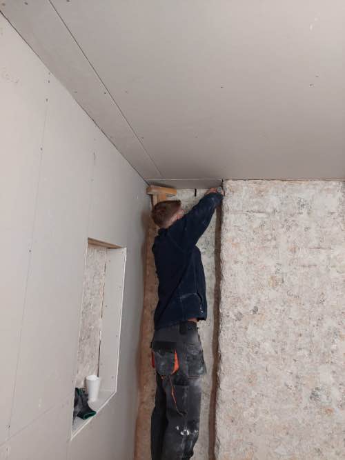 person fixing plasterboards to a ceiling on his training course