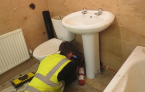 person soldering behind a toilet