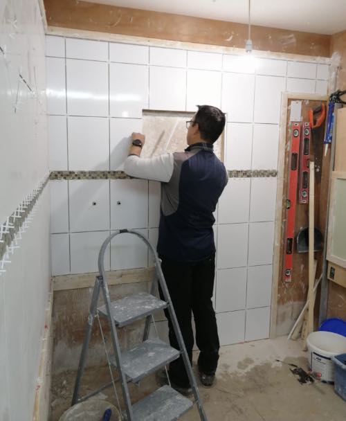 person fitting tile trim around a window opening