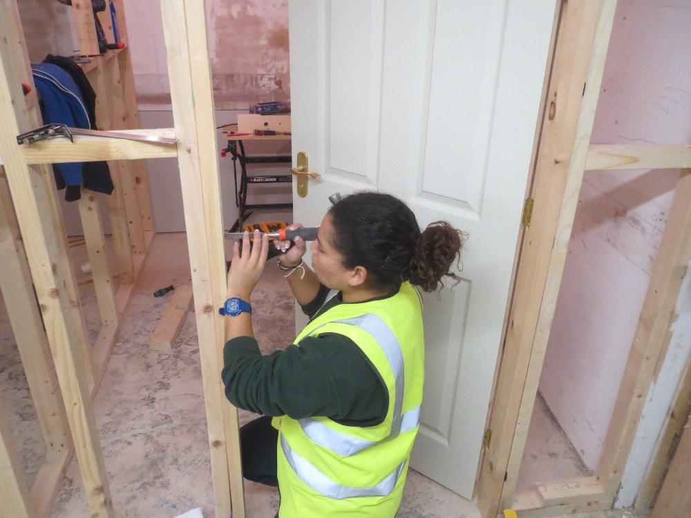 lady on carpentry course cutting door frame for latch