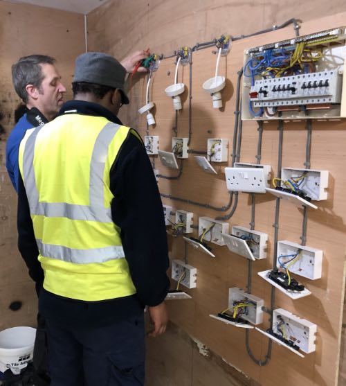 person being shown how to test electrical work