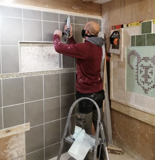 person from Birmingham applying silicon on our tiling course