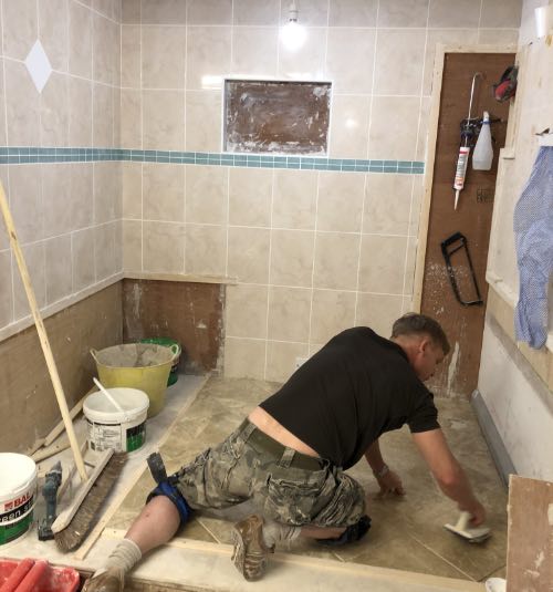 person from kent tiling a floor on a tiling course in stoke-on-trent