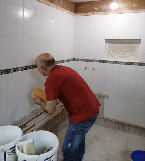 person from manchester cleaning grout from tiles on a tiling course in stoke-on-trent