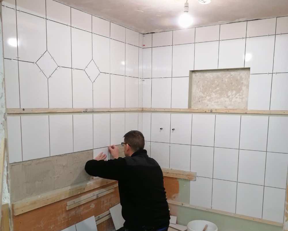 person fixing tiling spaces to tiles