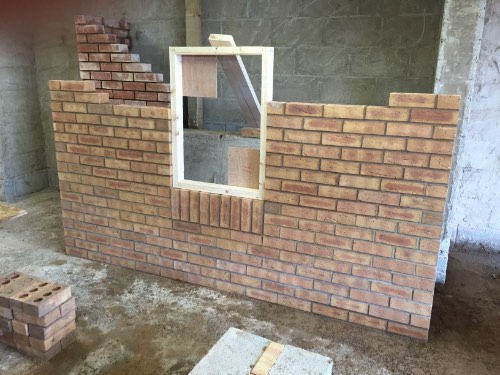 a part built brick wall showing the window former on top of brick on brick